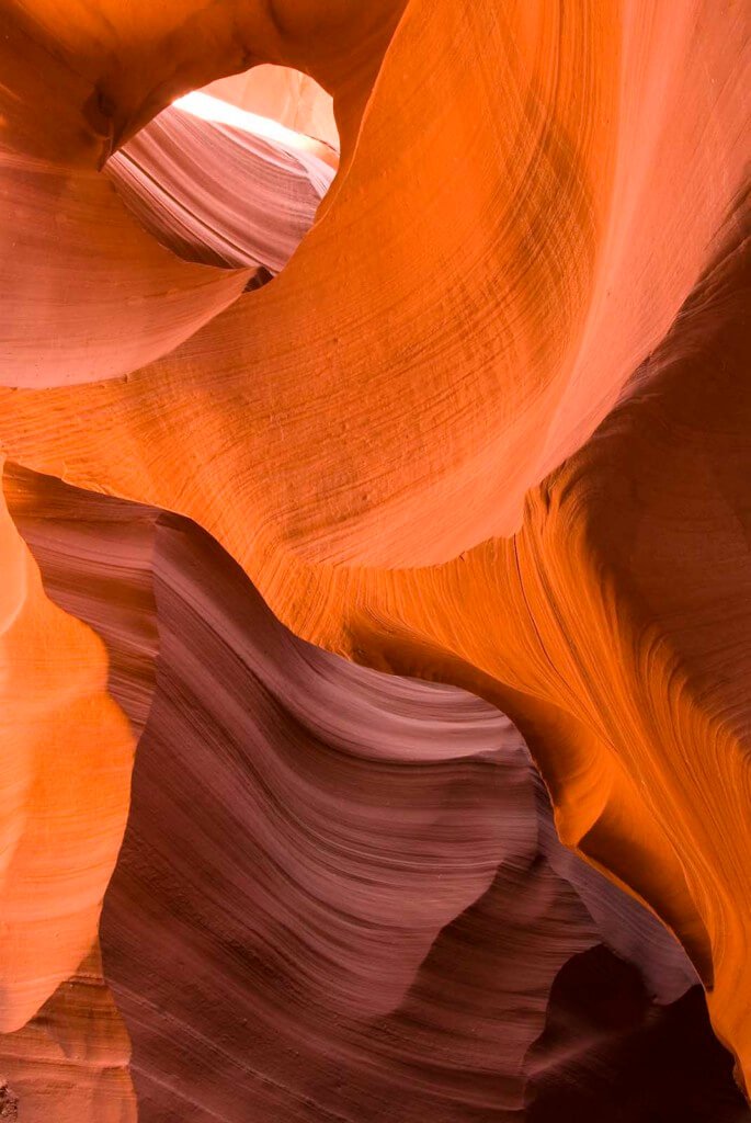 Perfect light: Brilliant oranges and reds from sunlight filtering into a slot canyon. For narrow slot canyons the “magic hour” for photography is not early morning or late evening. Usually it’s close to high noon with the sun directly over the canyon. Only then does the light penetrate, causing the sandstone to come alive and glow.