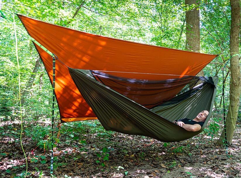man laying in hammock with orange tarp overhead