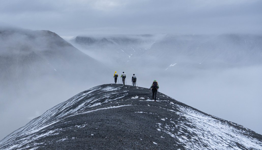 hikers traverse a ridgeline in the rain in alaska