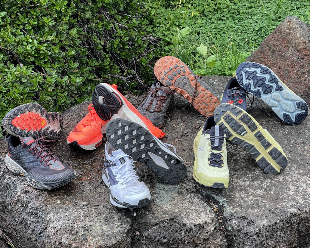 various trail running shoes laid out to show tread and upper