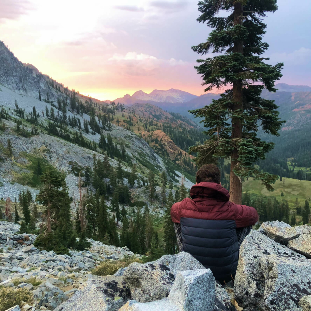 hiker in down jacket watches sunset