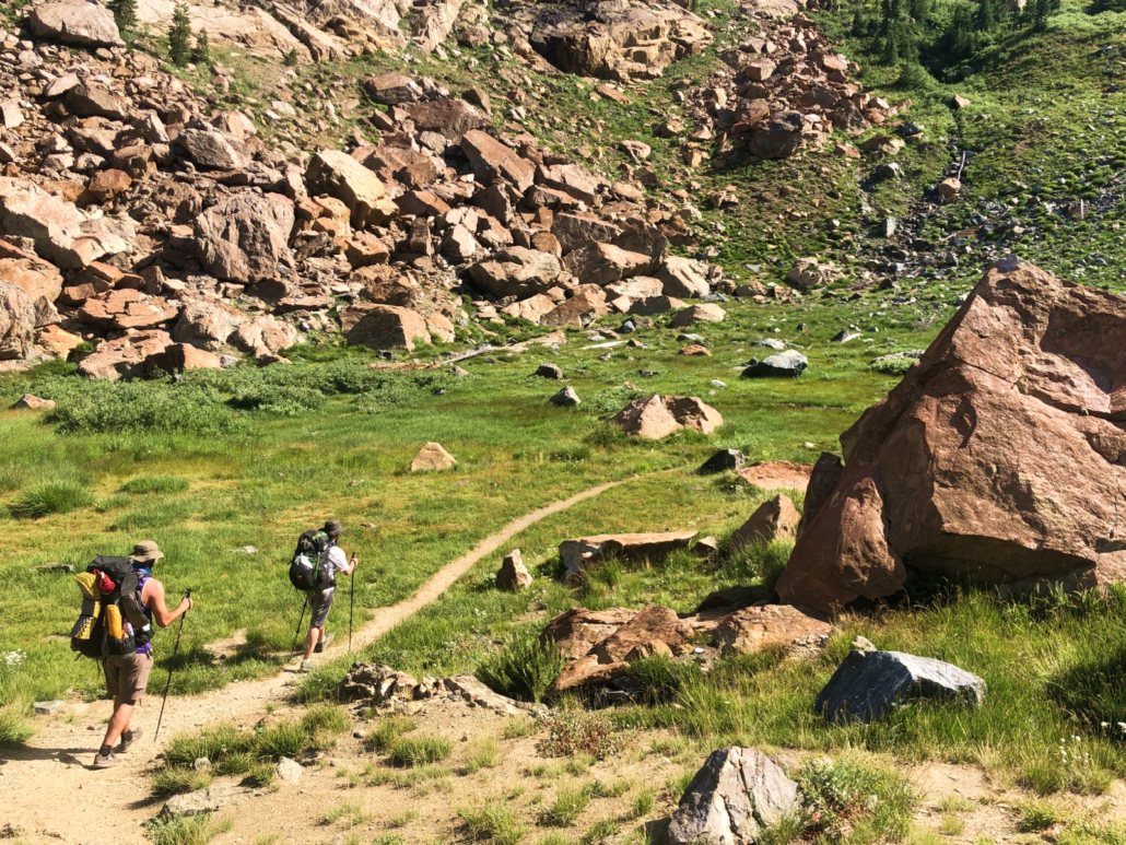 hikers in a grassy and rocky meadow