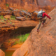 a man in hiking pants climbs through desert sandstone