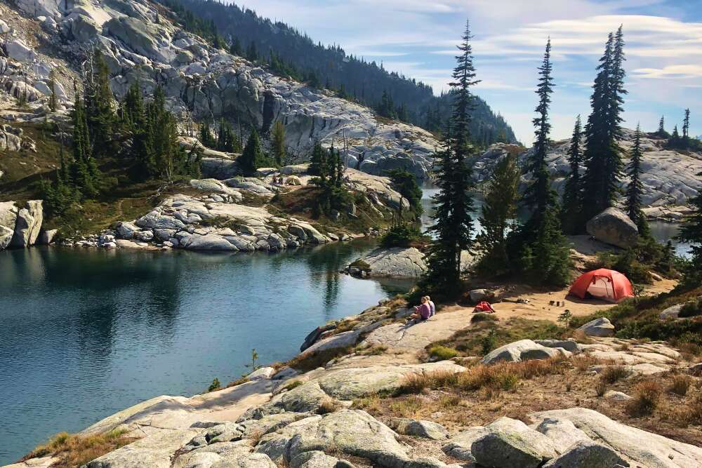 a 3 person backpacking tent next to a lake