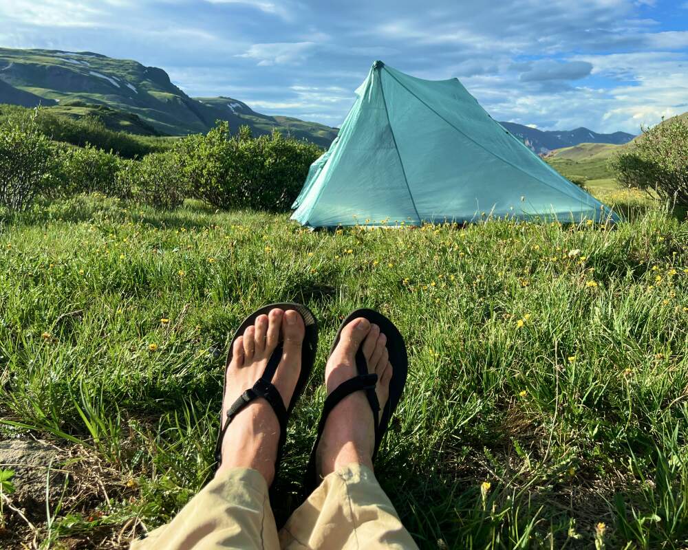 Wearing backpacking sandals in front of a backpacking tent Wearing backpacking sandals in front of a backpacking tent